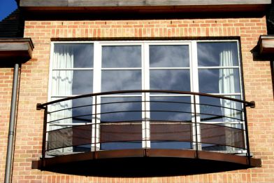 Structure d‘un balcon en lisse et en tôle perforée, le tout de couleur rouille.